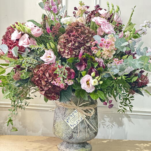COPA DE CEMENTO CON FLORES DE TEMPORADA EN TONOS ROSAS