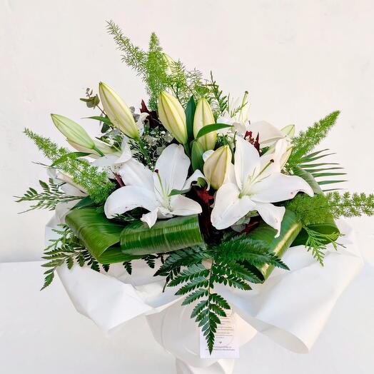 Bouquets of white Oriental lilies with baby's breath and assorted greenery.